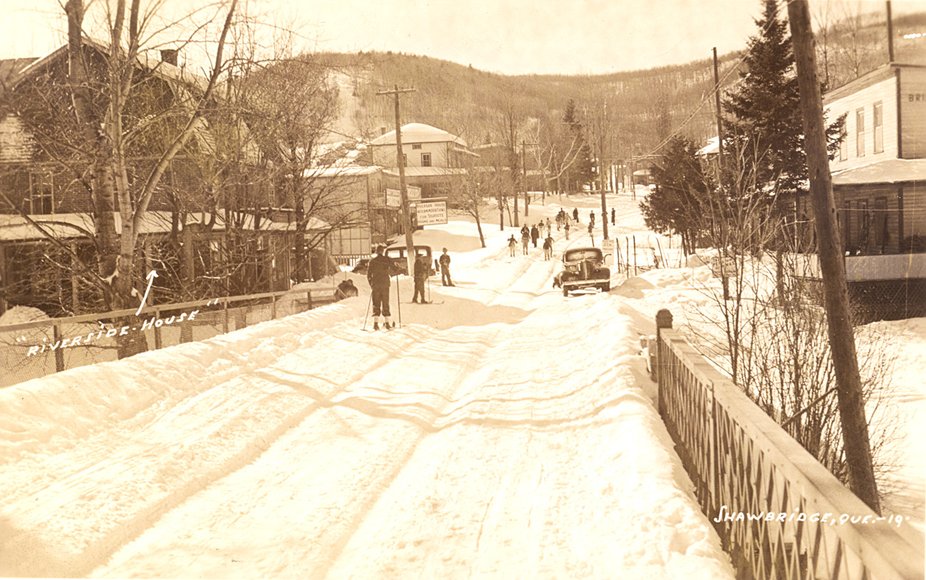 Skieurs traversant le pont Shaw vers les pentes de ski du Vieux-Prévost. À gauche, le Riverside House, et à droite, le Bridge House - Collection Sheldon Segal