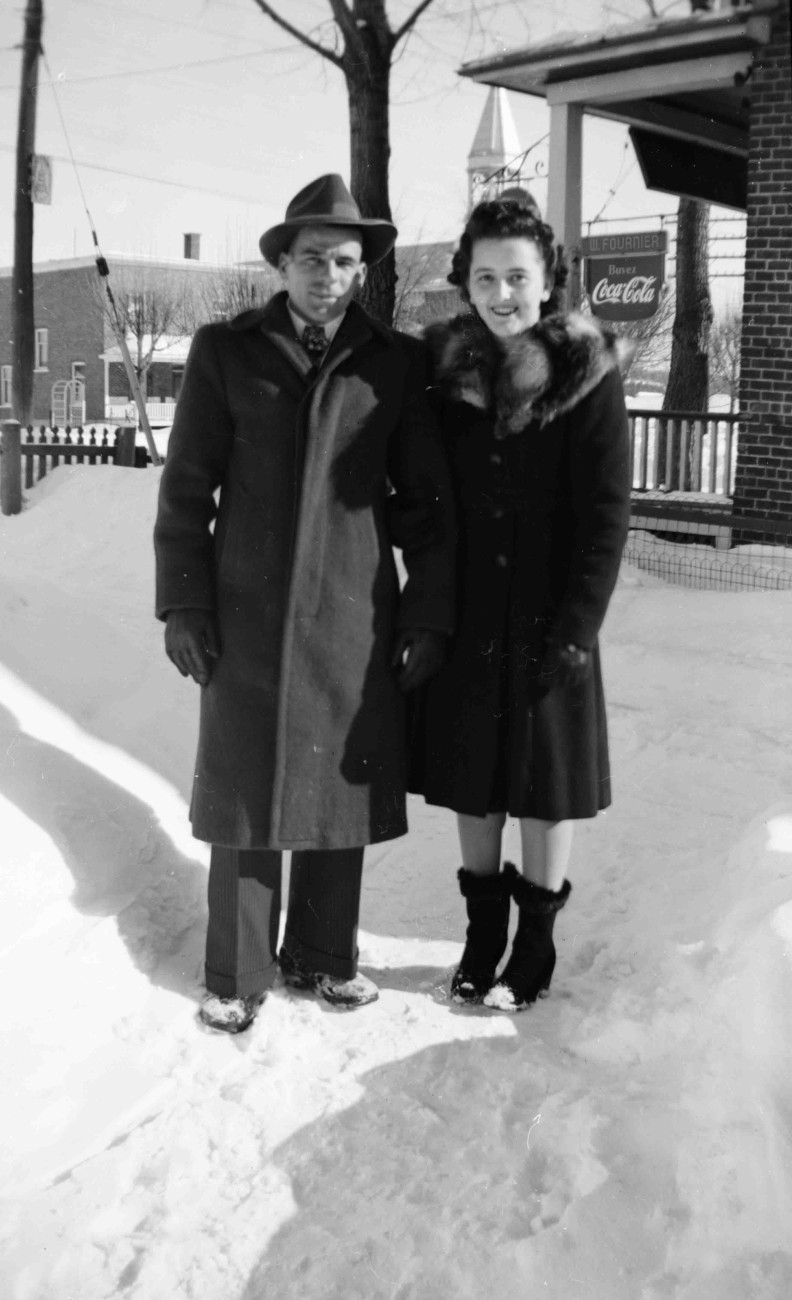 Hélène Brosseau et Bernard Paquin. En arrière-plan, l'annonce Coca-Cola du Magasin Venne ainsi que le presbytère et l'église Saint-François-Xavier - Collection Famille Brosseau