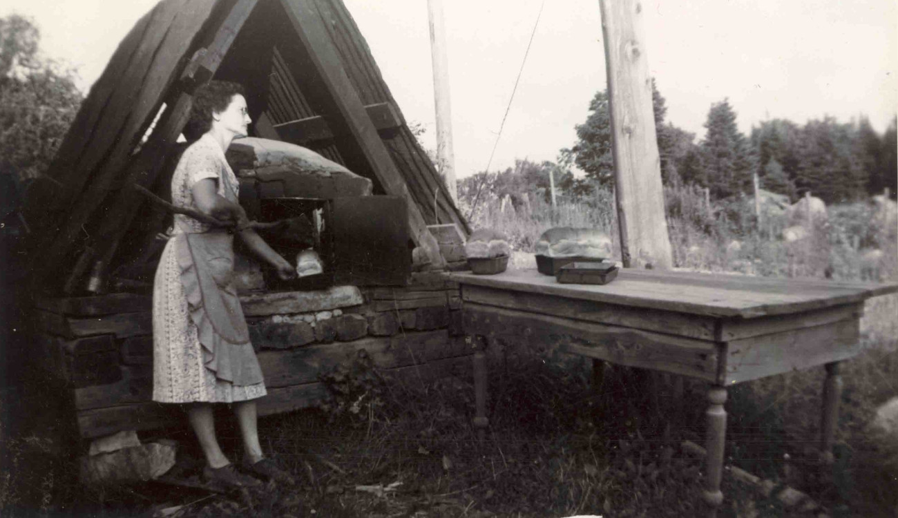 Le four à pain de la famille Brosseau. On y voit Alphonsine qui retire des pains du four dans les années 1940. Le four à pain a longtemps résisté à l'usure du temps et était encore visible au début des années 1980 - Collection Famille Brosseau