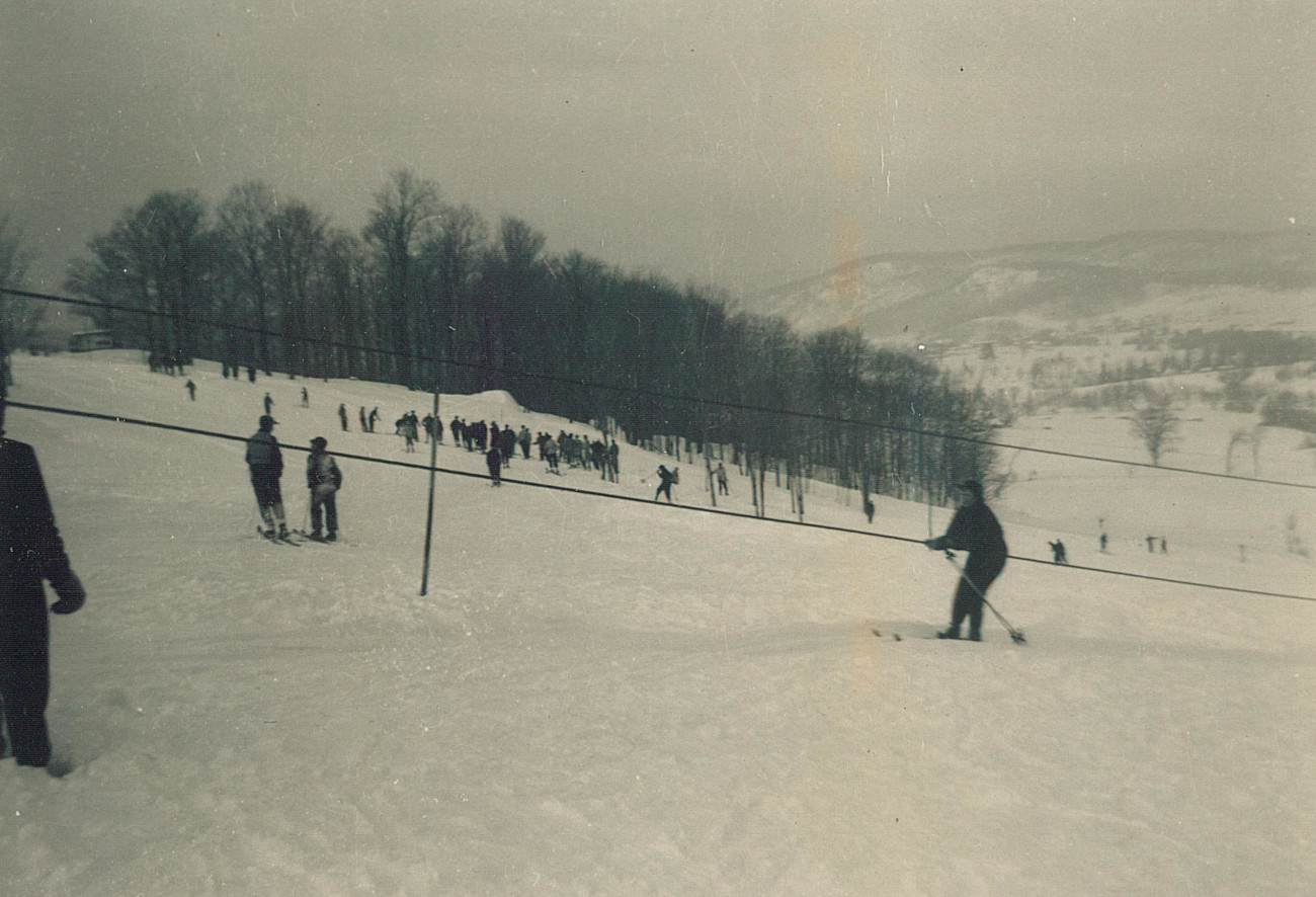 Un skieur bien accrochée au câble de remonte-pente du Sommet Parent entre 1949 et 1955 avec une belle vue sur les falaises du Vieux-Shawbridge au loin - Collection Luc Parent